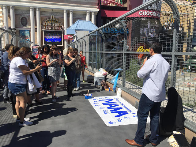 Passersby and volunteers take photos of a canvas created during an event on the Las Vegas Strip on Sept. 16, 2016. The handprints symbolize passersby's intent to vote, and a man yelling racial slu ...