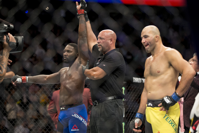 Anthony Johnson, left, raises his arm in victory after his first round knockout win against Glover Teixeira in the light heavyweight bout during UFC 202 at T-Mobile Arena on Saturday, Aug. 20, 201 ...
