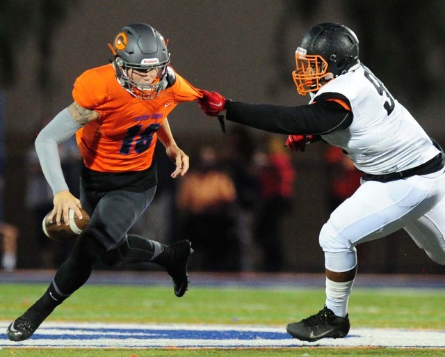 Bishop Gorman quarterback Tate Martell rushes for a first down while being chased by Cocoa, Fla., defensive tackle Ian Newton in the first half of their prep football game at Bishop Gorman High S ...