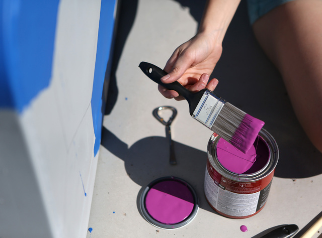 Tatiana Hantig dips her brush in magenta paint while painting a utility box in the pattern of a desert tortoise outside of Desert Breeze Park Community Center Oct. 21, 2013, in Las Vegas as part o ...