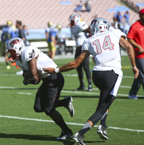 UNLV Rebels quarterback Kurt Palandech (14) passes off the ball to UNLV Rebels running back Lexington Thomas (3) while warming up ahead of a football game against UCLA at the Rose Bowl in Pasadena ...