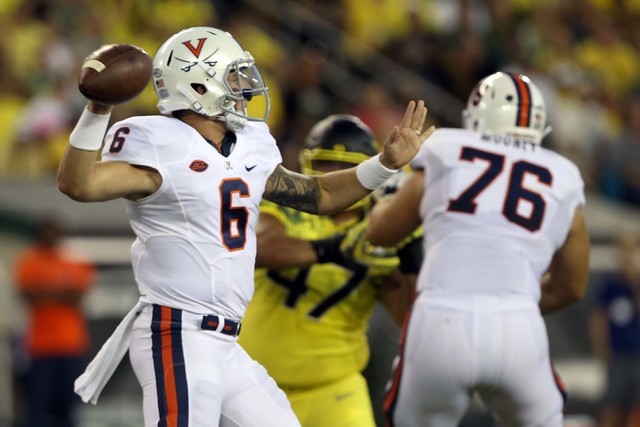 Virginia quarterback Kurt Benkert, left, drops back to pass against Oregon during the first quarter of an NCAA college football game Saturday, Sept. 10, 2016 in Eugene, Ore. (AP Photo/Chris Pietsch)