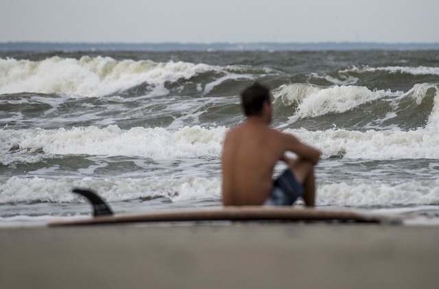 Eric Dunn sit on the northern end of Tybee Island's beach watching larger than average waves roll in as a result of approaching Hurricane Matthew, Tuesday, Oct. 4, 2016 in Tybee Island, Georgia.   ...