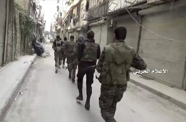 In this still image taken from video provided by the Syrian government-controlled Syrian Central Military Media, government troops patrol inside the Bustan Al-Basha neighborhood of Aleppo, Syria o ...