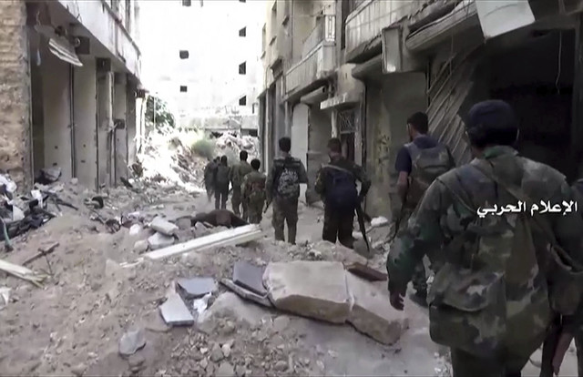In this still image taken from video provided by the Syrian government-controlled Syrian Central Military Media, government troops patrol inside the Bustan Al-Basha neighborhood of Aleppo, Syria o ...
