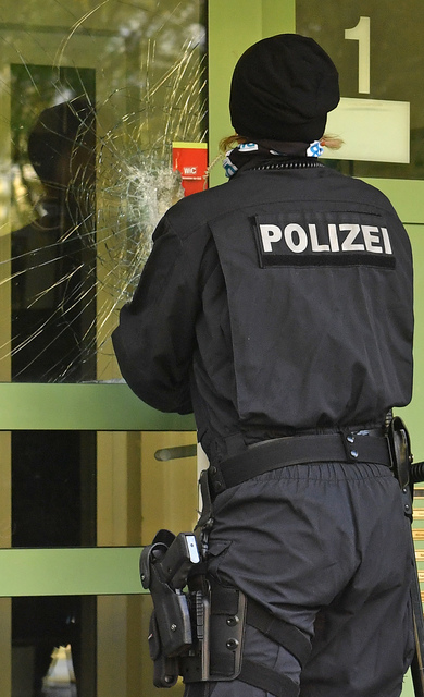 A policewoman closes the damaged door of an apartment building in the Yorck area of Chemnitz, eastern Germany, Sunday, Oct. 9, 2016. German police searched nationwide for a 22-year-old Syrian man ...