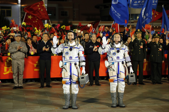 Chinese astronauts Jing Haipeng, right, and Chen Dong, wave farewell before being launched into space. The astronauts will dock with an experimental space station and stay there for 30 days to tes ...