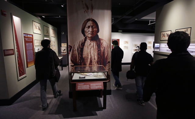 Patrons pass a portrait featuring Sitting Bull, part of the Hall of North American Indian exhibit, at the Peabody Museum of Archaeology & Ethnology at Harvard University in Cambridge, Mass., T ...