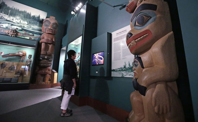 A visitor stands among totem poles as she watches a video as part of Hall of the North American Indian exhibit, at the Peabody Museum of Archaeology & Ethnology at Harvard University. (Charles ...