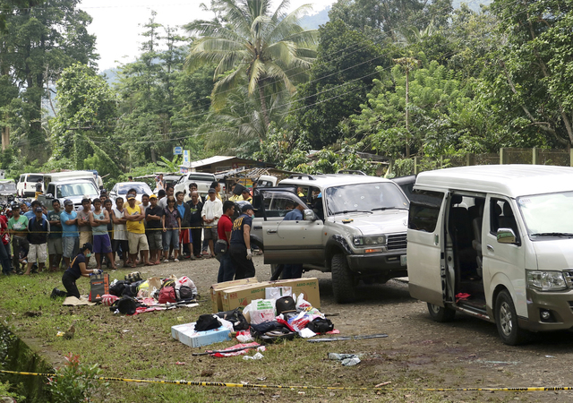 Residents watch as police inspect the contents of the vehicles following a gunbattle on Friday that killed Mayor Samsudin Dimaukom of southern Datu Saudi Ampatuan township and nine others. (AP Photo)
