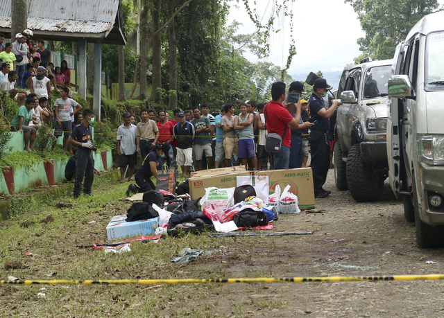 Residents watch as police inspect the contents of the vehicles following a gunbattle on Friday that killed Mayor Samsudin Dimaukom of southern Datu Saudi Ampatuan township and nine others. (AP Photo)
