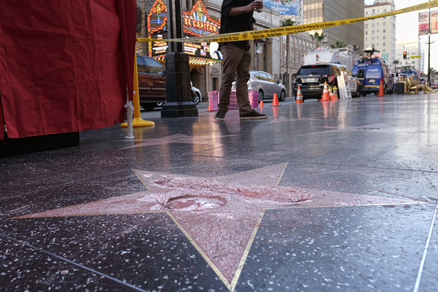 A man stands near a cordoned off area surrounding the vandalized star for Republican presidential candidate Donald Trump on the Hollywood Walk of Fame, Wednesday, Oct. 26, 2016, in Los Angeles. (R ...