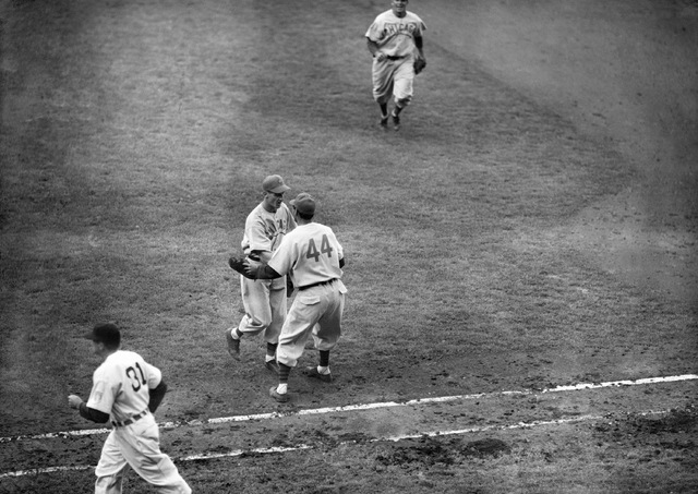 In this Oct., 3, 1945, file photo, Phil Cavarretta (44), of the Chicago Cubs, rushes over from first base to pitcher Hank Borowy to congratulate him on his six-hit, 9-0, victory over the Detroit T ...