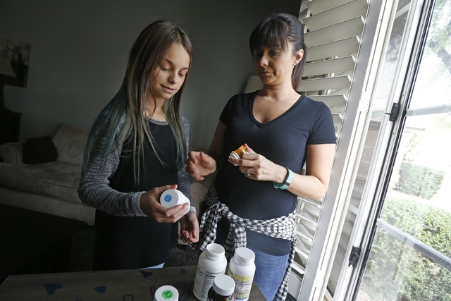 Nicole Robinson, right, with daughter Riley, 11, go over the variety of medications Riley is required to take on a daily basis Thursday, Oct. 27, 2016, in Cave Creek, Ariz. (Ross D. Franklin/The A ...