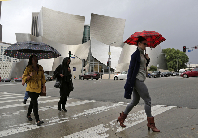 Umbrellas protect people from rain as they walk past the Frank Gehry-designed Disney Hall in downtown Los Angeles on Friday, Oct. 28, 2016. (Nick Ut/The Associated Press)