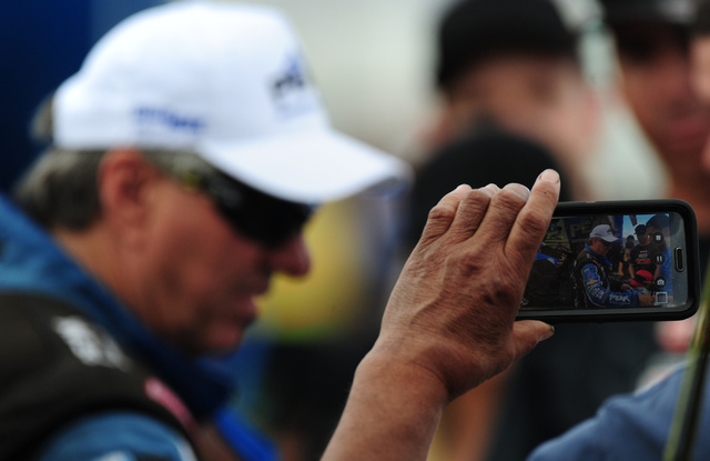 A fan takes a cell phone photo of Funny Car driver John Force signing autographs in between qualifying session for the NHRA Mello Yello Series Toyota Nationals at The Strip at Las Vegas Motor Spee ...