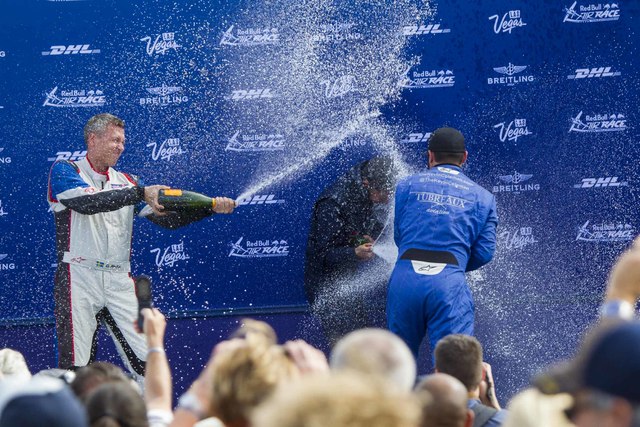 Pilots Daniel Ryfa, left, and Kevin Coleman, right, spray champagne on Florian Berger after receiving their race results for the Challenger Cup air race during a podium celebration at the Las Vega ...