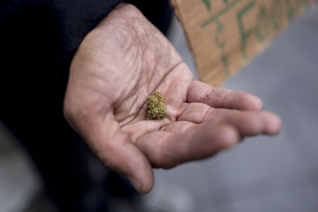 A man holding a bud of marijuana in his palm after a pedestrian slipped it into his hand on the 16th St. Mall after she read his sign asking for both money and weed Friday, Aug. 2, 2016, in Denver ...