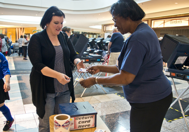 Mary Miller, right hands an "I Voted" sticker to Jennifer Robbins as she leaves the polls during the first day of early voting at the Galleria at Sunset in Henderson on Saturday ...
