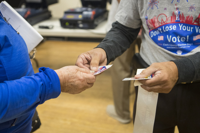 Edge worker Rudi de Leon, right, hands a voter a sticker during early voting at the East Las Vegas Community Center in Las Vegas on Saturday, Oct. 22, 2016. Loren Townsley/Las Vegas Review-Journal ...