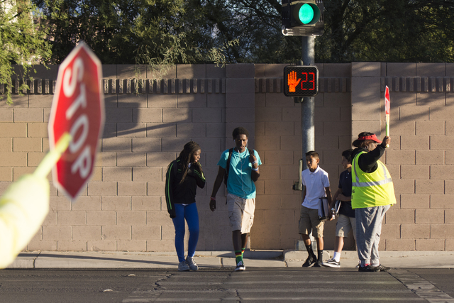 Crossing guards Rhonda Enabulele, right, and Patricia Bass assist children in crossing Lake Mead Boulevard at Tonopah Drive before classes at West Preparatory Academy in Las Vegas, Thursday, Oct.  ...