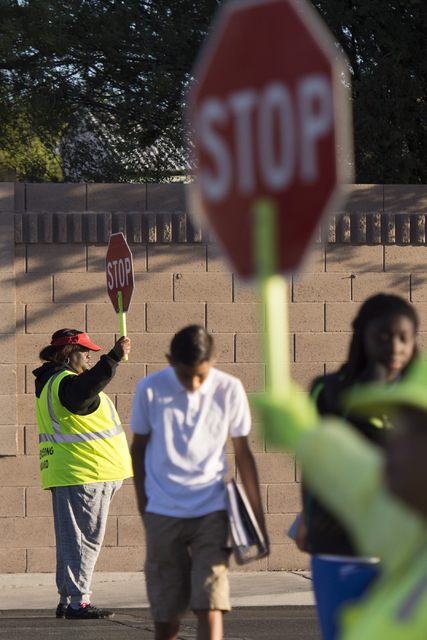 Crossing guards Rhonda Enabulele, left, and Patricia Bass assist children in crossing Lake Mead Boulevard at Tonopah Drive before classes at West Preparatory Academy in Las Vegas, Thursday, Oct. 6 ...