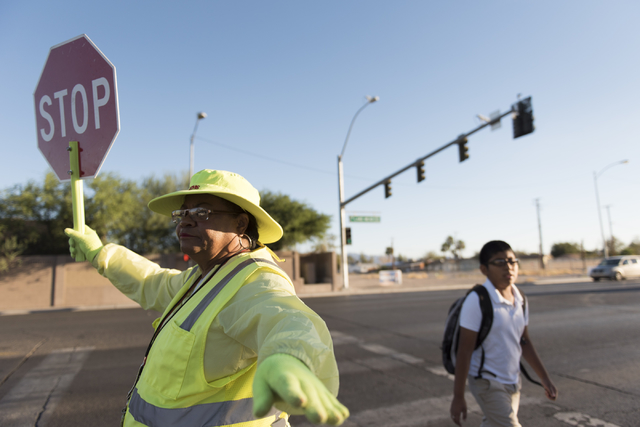 Crossing guard Patricia Bass assists a child in crossing Lake Mead Boulevard at Tonopah Drive before classes at West Preparatory Academy in Las Vegas, Thursday, Oct. 6, 2016. (Jason Ogulnik/Las Ve ...