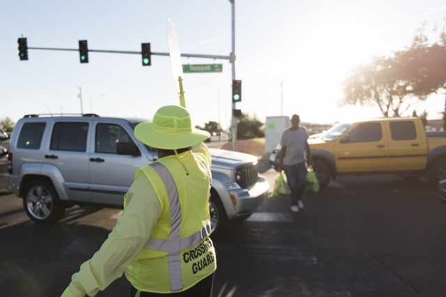 Crossing guard Patricia Bass assists a man in crossing the obstructed crosswalk on Tonopah Drive at Lake Mead Boulevard during morning rush hour in Las Vegas, Thursday, Oct. 6, 2016. (Jason Ogulni ...