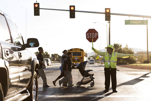 Crossing guard Patricia Bass assists children and parents in crossing Lake Mead Boulevard at Tonopah Drive before classes at West Preparatory Academy in Las Vegas, Thursday, Oct. 6, 2016. (Jason O ...