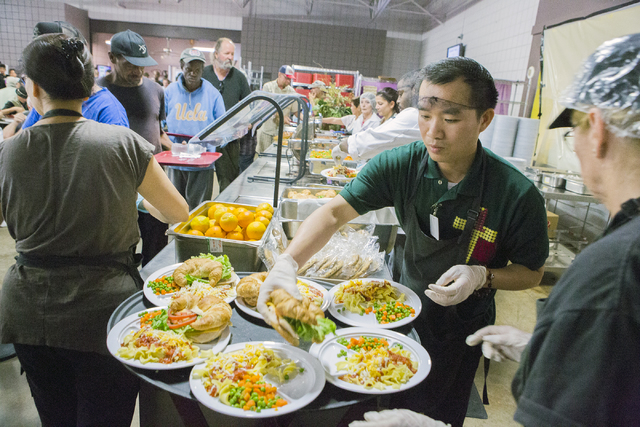 Volunteer Louis Nguyen places a sandwich on a plate during lunch at Catholic Charities of Southern Nevada Aug. 31. View file photo