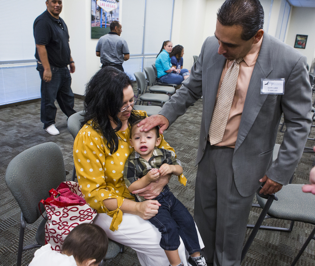 Former prisoner Edward Vargas, left, touches his son, Emmanuel, 19 months, while his wife, Maria, sits after his graduation from Hope for Prisoners at Metropolitan Police Department headquarters. ...