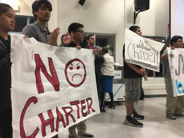 Students hold signs during a rally in the cafeteria at West Preparatory Institute for Academic Excellence in Las Vegas on Tuesday, Oct. 18, 2016, to protest the possibility of a charter-school tak ...