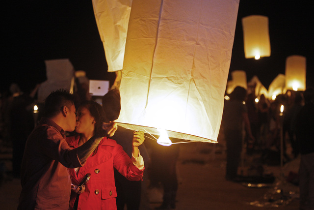 Junnie and Jade Ranole, from Las Vegas, kiss as they inflate a paper lantern at the RiSE Festival Saturday, Oct. 18, 2014 on a dry lake bed near Jean.  (Sam Morris/Las Vegas Review-Journal)