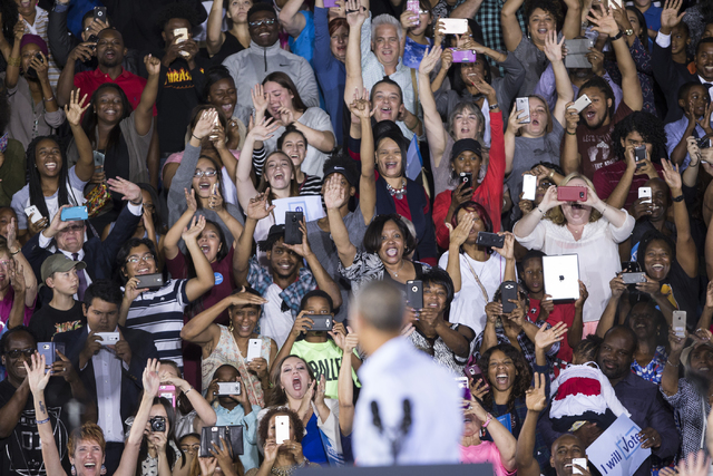 Supporters wave at President Barack Obama as he takes the stage for a speech during a campaign rally for Democratic presidential nominee Hillary Clinton at Cheyenne High School on Sunday, Oct. 23, ...