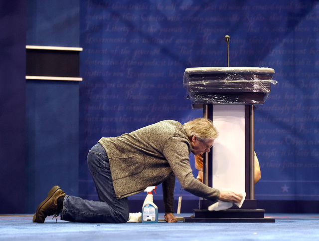 Michael Foley cleans one of the podiums on the debate set at the Thomas & Mack Center at UNLV Monday, Oct. 17, 2016, in Las Vegas. The third and final presidential debate is scheduled for Wedn ...