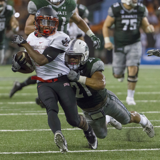 UNLV running back Lexington Thomas, left, breaks a tackle by Hawaii defensive back Damien Packer (21) and runs in for a touchdown late in the fourth quarter of an NCAA college football game, Satur ...