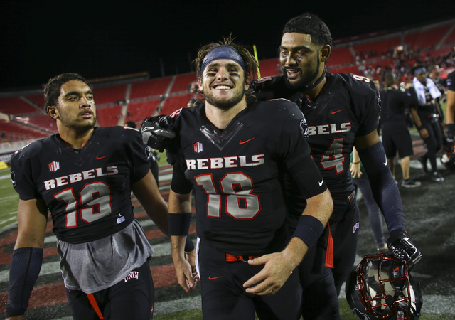 UNLV quarterback Dalton Sneed (18) walks off the field with teammates defensive lineman Mark Finau (19) and defensive lineman Jeremiah Valoaga (94) after defeating Fresno State in a football game  ...