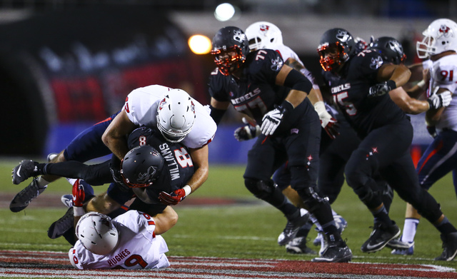 UNLV running back Charles Williams (8) is tackled by Fresno State linebacker Brandon Hughes (19) and Fresno State punter Blake Cusick (47) during a football game at Sam Boyd Stadium in Las Vegas o ...