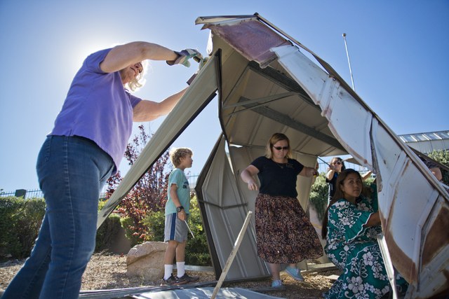 Miriam Elmquist is helped by a group of volunteers from the Church of Jesus Christ of Latter-day Saints to disassemble a metal shed that blew over her wall and into the parking lot of Horizon Vete ...