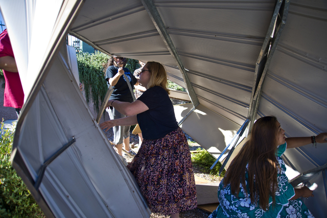 Church of Jesus Christ of Latter-day Saints missionaries Keloy Dalton of Indiana, left, and Sarah Haley of Texas help to disassemble a metal shed that blew over a wall and into the parking lot of ...