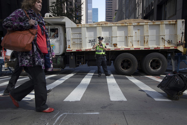 FILE- In this Sept. 24, 2015 file photo, a police office stands guard at a loaded dump truck that serves as a barricade along the perimeter of St. Patrick's Cathedral before the arrival of Pope Fr ...