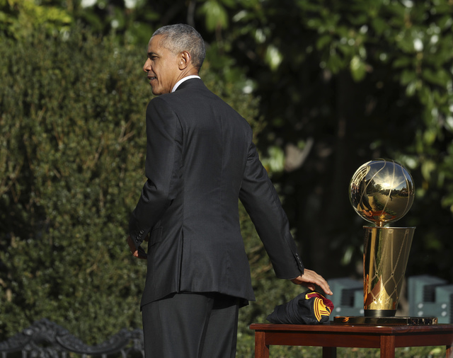 President Barack Obama places a Cleveland Cavaliers team jersey on a table next to the Larry O'Brien Championship trophy during a ceremony where he honored the 2016 NBA Champion Cavaliers, Thursda ...