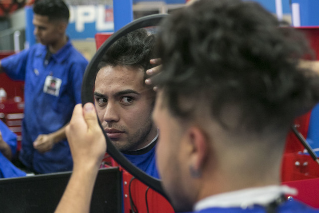 Barber student Robert Luna, 22, looks over his hairline while getting a haircut from fellow student Gabriel Avila, 21, left, during class at the Masterpiece Barber College in Las Vegas, Thursday,  ...