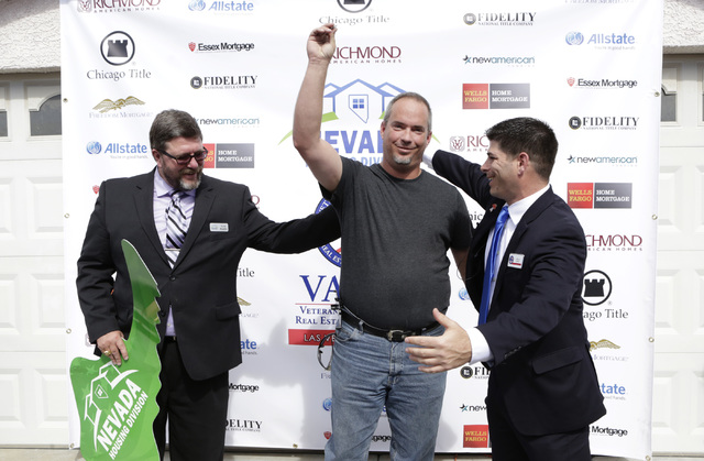 U.S. Army Cpl. Christopher Hudson, center, reacts after receiving the keys to his newly renovated, mortgage-free home in Centennial Hills as Billy Alt, president of the Veterans Association of Rea ...