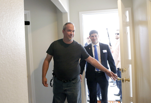 U.S. Army Cpl. Christopher Hudson, left, flanked by Billy Alt, president of the Veterans Association of Real Estate Professionals, right, enters his newly renovated home Oct. 14, 2016, in Las Vega ...