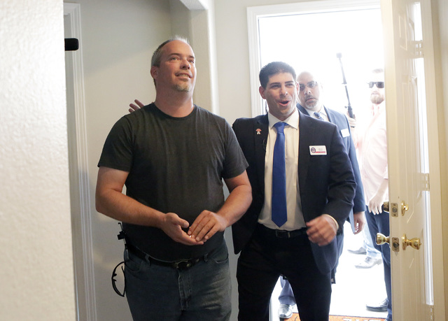U.S. Army Cpl. Christopher Hudson, left, flanked by Billy Alt, president of the Veterans Association of Real Estate Professionals, right, enters to his newly renovated home Oct. 14, 2016. Bizuayeh ...