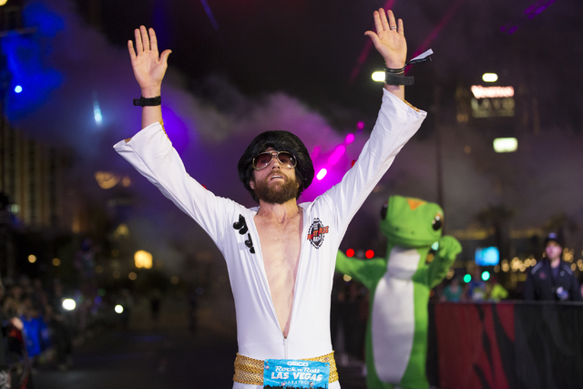 Michael Wardian in costume as Elvis raises his arms in victory as he completes the Rock-n-Roll Marathon for men in first place at the Strip near The Mirage hotel-casino on Sunday, Nov. 13, 2016, i ...