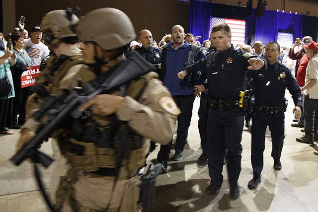A man is escorted by law enforcement officers moments after Donald Trump was rushed offstage by Secret Service agents during a campaign rally in Reno, Nev., on Saturday, Nov. 5, 2016. (Evan Vucci/ ...
