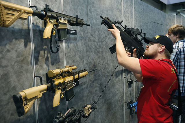 In this Jan. 19, 2016 file photo, Nolan Hammer looks at a gun at the Heckler & Koch booth at the Shooting, Hunting and Outdoor Trade Show in Las Vegas.  (AP Photo/John Locher, File)