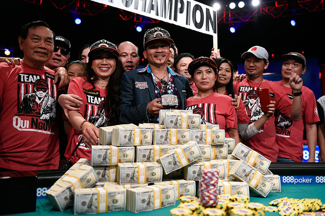 Qui Nguyen of Las Vegas, surrounded by family and friends, stands with a pile of cash and his championship bracelet after eliminating Gordon Vayo at the final table at the 2016 World Series of Pok ...